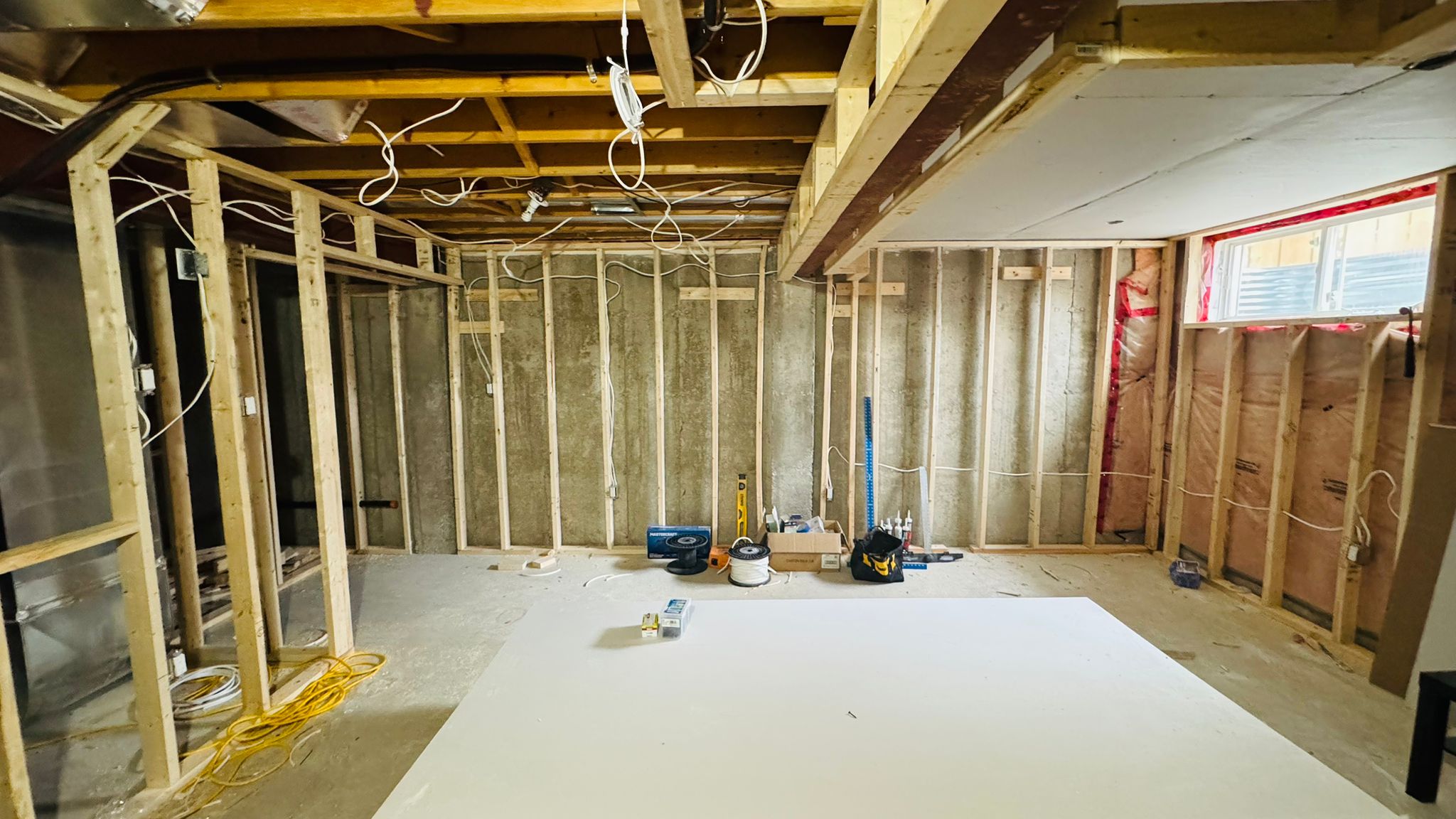 The same basement before renovation — bare concrete walls and open framing