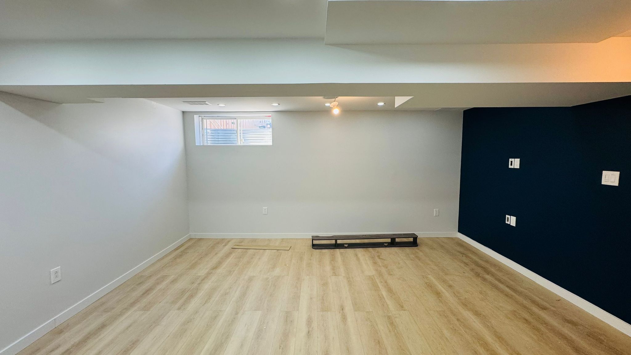 Finished basement with a bold navy accent wall and recessed lighting