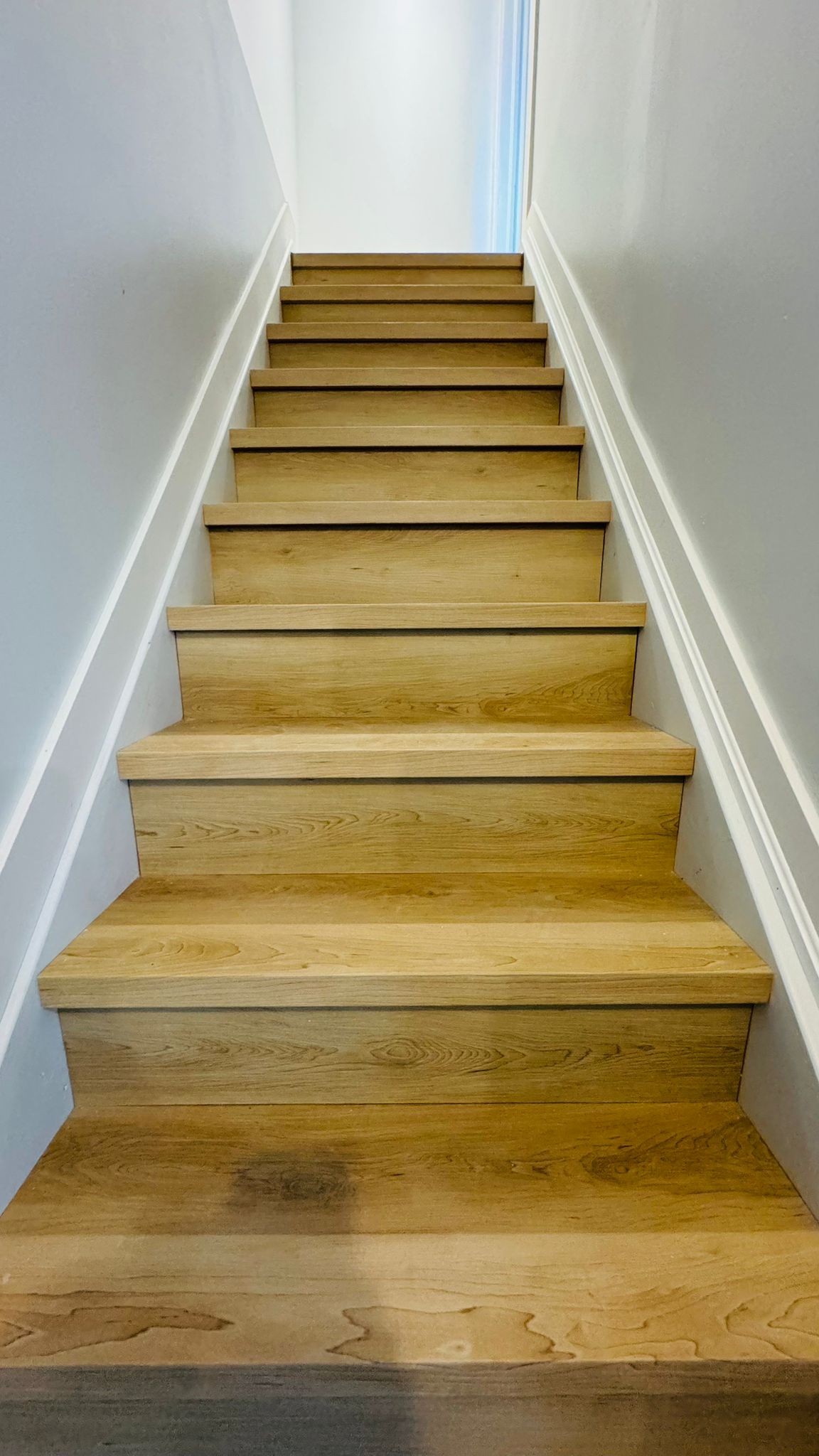 New oak-tone vinyl plank staircase with crisp white painted stringers
